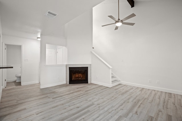 unfurnished living room with high vaulted ceiling, light hardwood / wood-style floors, beamed ceiling, and ceiling fan