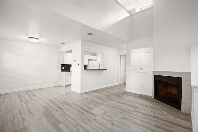 unfurnished living room featuring a high ceiling and light wood-type flooring