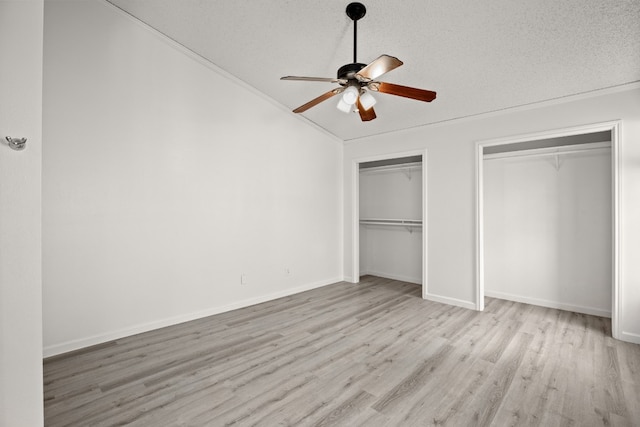 unfurnished bedroom with ornamental molding, a textured ceiling, light hardwood / wood-style floors, two closets, and ceiling fan