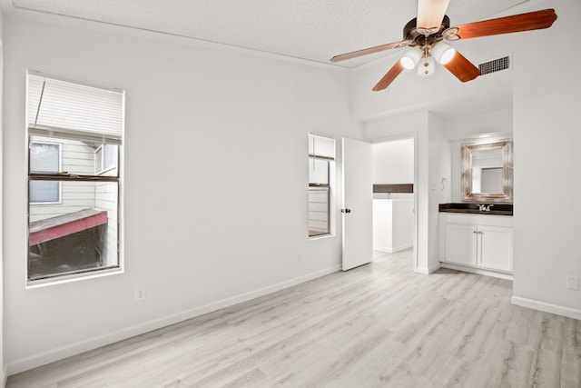 unfurnished living room featuring ceiling fan, a textured ceiling, sink, and light hardwood / wood-style flooring