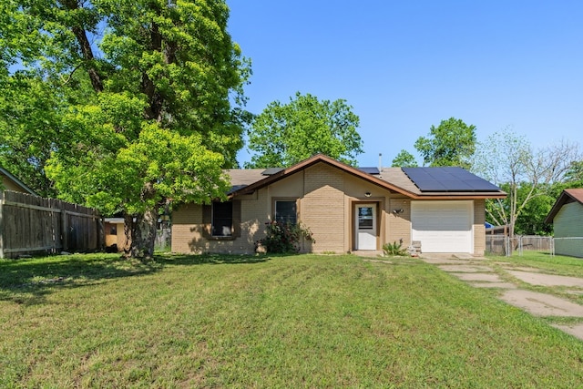 single story home featuring a garage, solar panels, and a front lawn