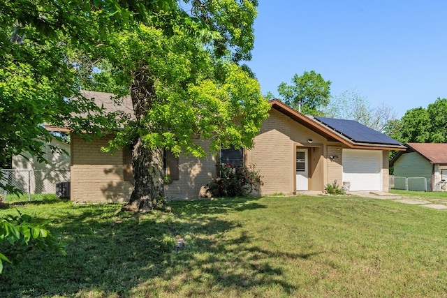 view of front of property featuring a front yard, solar panels, and a garage