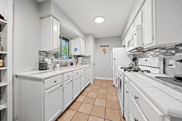 kitchen with white cabinetry, sink, white appliances, and light tile patterned floors