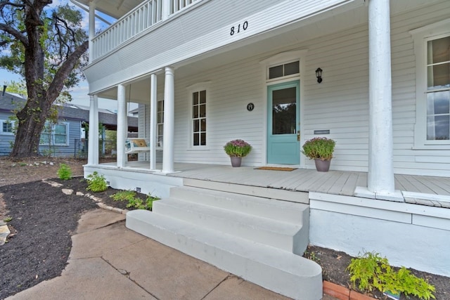 entrance to property with covered porch and a balcony