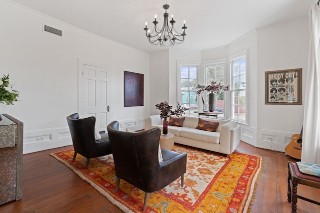 living room with a notable chandelier, hardwood / wood-style flooring, and crown molding