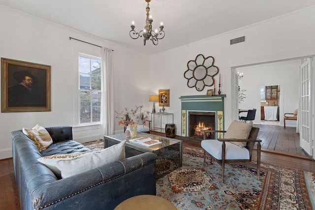 living room with a notable chandelier, dark hardwood / wood-style floors, and crown molding