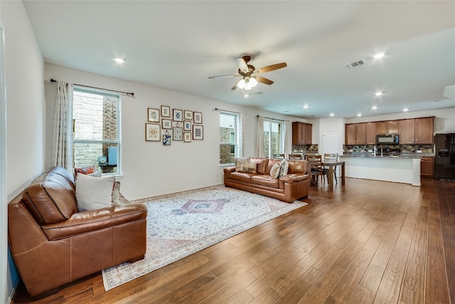 living room with dark hardwood / wood-style flooring and ceiling fan