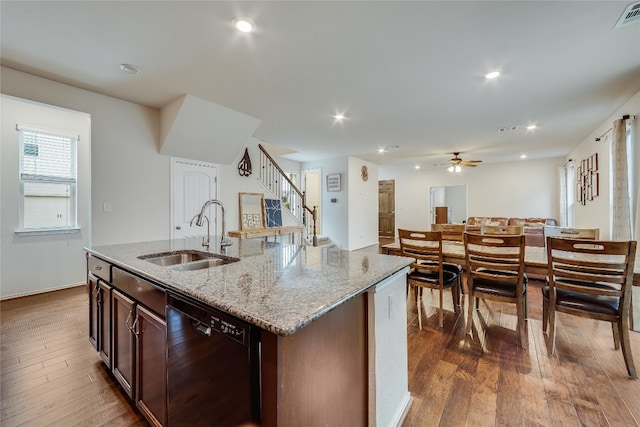 kitchen featuring black dishwasher, dark wood-type flooring, sink, and an island with sink