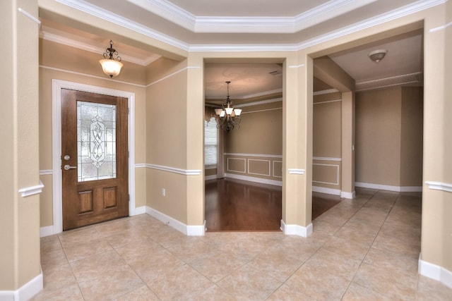 foyer entrance with an inviting chandelier, light tile patterned floors, and ornamental molding