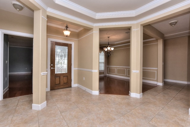 tiled foyer with a tray ceiling, a notable chandelier, and ornamental molding