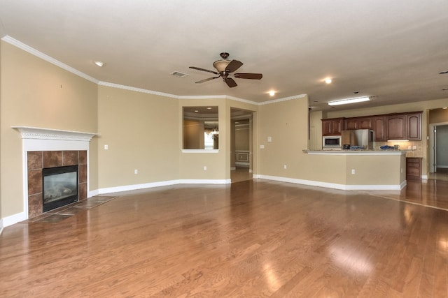 unfurnished living room with hardwood / wood-style floors, a fireplace, ceiling fan, and ornamental molding