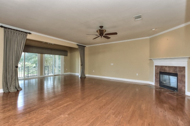 unfurnished living room featuring hardwood / wood-style floors, ceiling fan, a tile fireplace, and crown molding