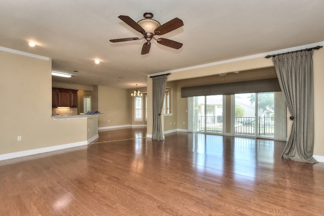 unfurnished living room featuring hardwood / wood-style floors, ornamental molding, and ceiling fan with notable chandelier