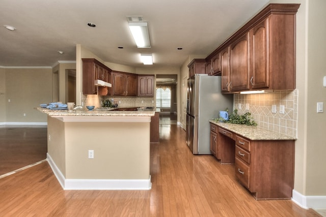 kitchen with light stone countertops, kitchen peninsula, light hardwood / wood-style floors, and crown molding