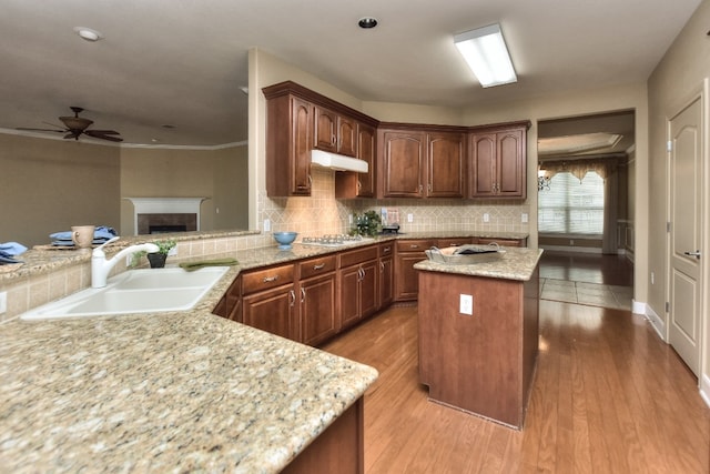 kitchen featuring ornamental molding, sink, hardwood / wood-style flooring, kitchen peninsula, and a center island