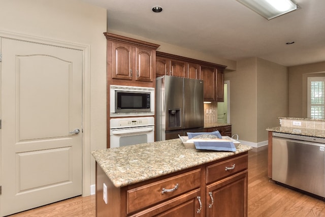 kitchen featuring light hardwood / wood-style floors, decorative backsplash, appliances with stainless steel finishes, and a center island