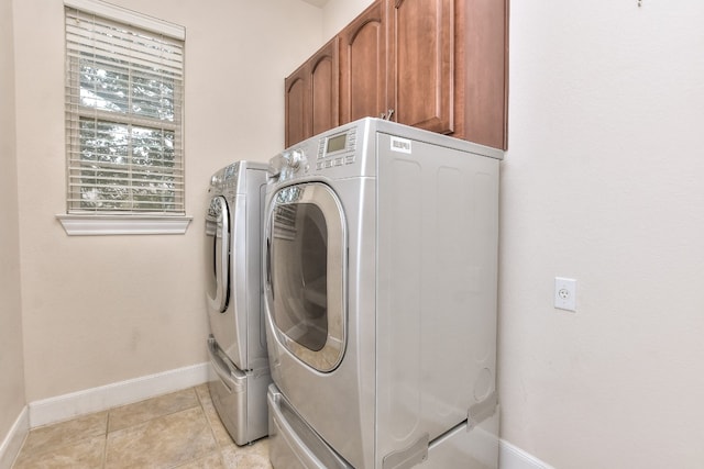 laundry room featuring cabinets, light tile patterned floors, and independent washer and dryer