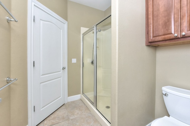 bathroom with a shower with shower door, tile patterned floors, and toilet