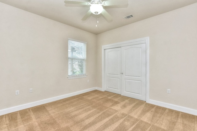 unfurnished bedroom featuring a closet, light colored carpet, and ceiling fan