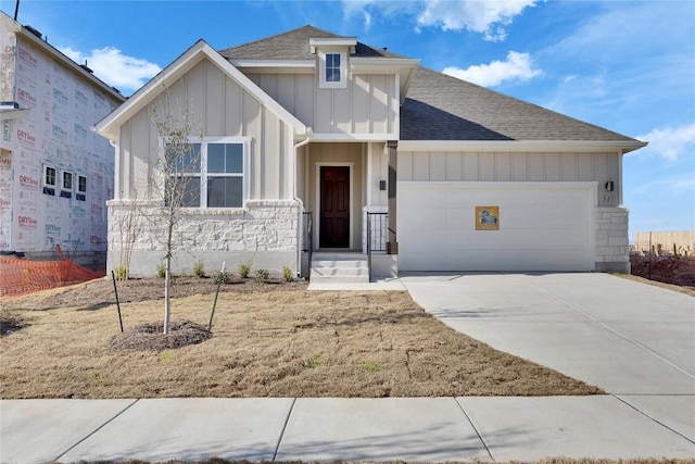 view of front of home featuring an attached garage, concrete driveway, board and batten siding, and roof with shingles