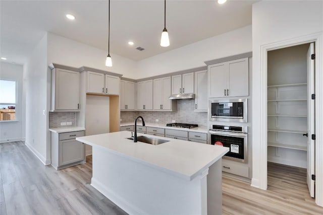 kitchen featuring visible vents, gray cabinetry, appliances with stainless steel finishes, light wood-style floors, and a sink