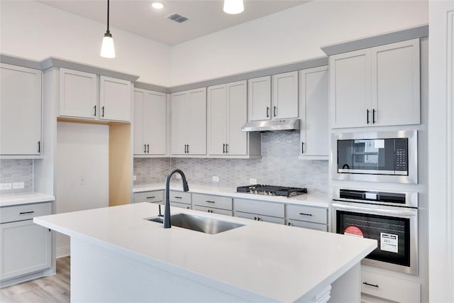 kitchen featuring visible vents, under cabinet range hood, light countertops, appliances with stainless steel finishes, and a sink