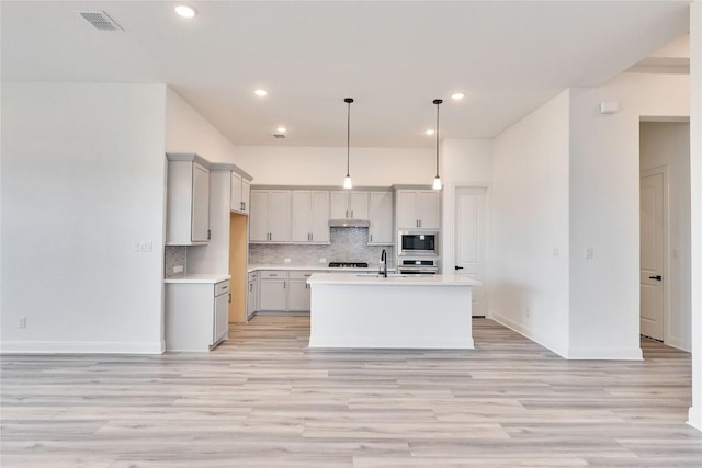 kitchen featuring visible vents, built in microwave, oven, a sink, and tasteful backsplash