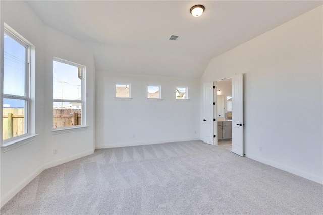 unfurnished room with visible vents, light carpet, baseboards, and vaulted ceiling