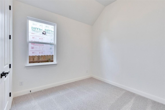 carpeted empty room with vaulted ceiling and baseboards