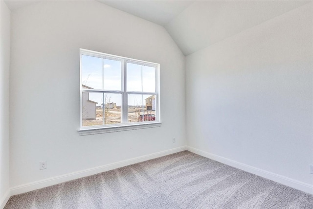 carpeted spare room featuring baseboards and lofted ceiling
