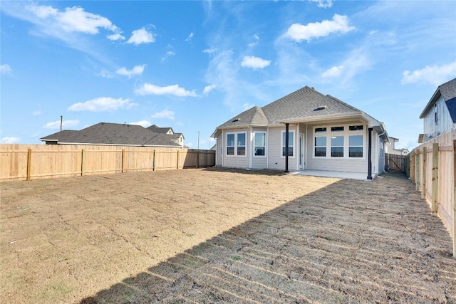 rear view of house featuring a fenced backyard
