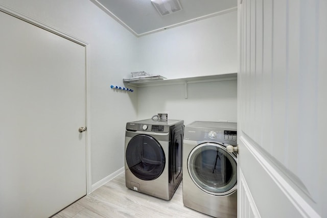 laundry room with light wood-type flooring and washing machine and dryer