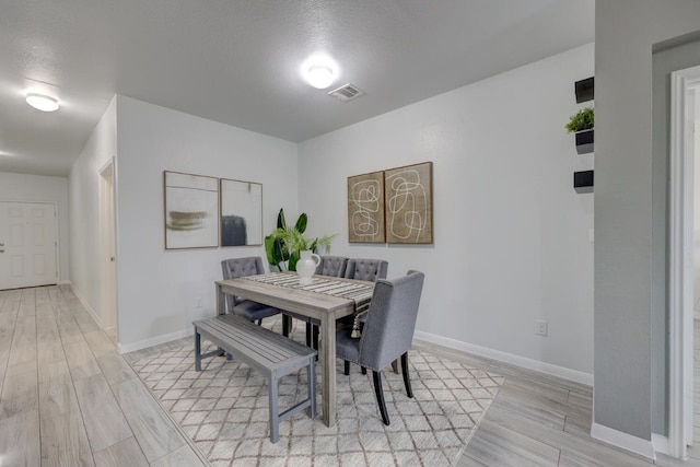 dining room featuring light hardwood / wood-style floors and a textured ceiling