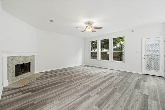 unfurnished living room featuring a fireplace, light hardwood / wood-style floors, and ceiling fan