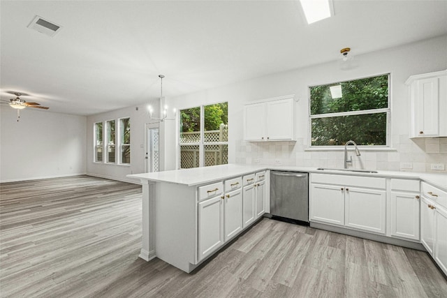 kitchen with white cabinets, sink, stainless steel dishwasher, light wood-type flooring, and kitchen peninsula