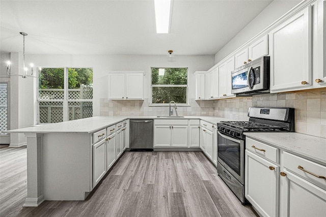 kitchen with kitchen peninsula, stainless steel appliances, white cabinets, and plenty of natural light