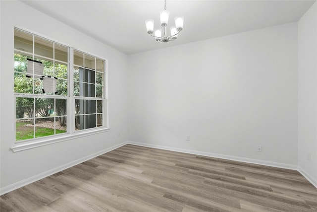 spare room featuring a chandelier and light hardwood / wood-style flooring