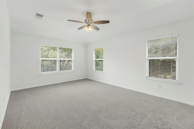 carpeted spare room featuring ceiling fan and plenty of natural light