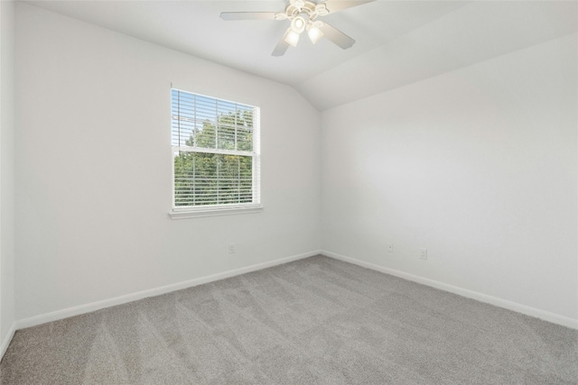 empty room with ceiling fan, light colored carpet, and vaulted ceiling