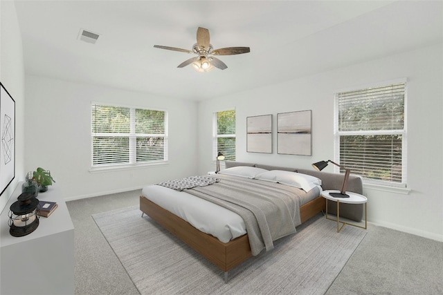 carpeted bedroom featuring multiple windows and ceiling fan