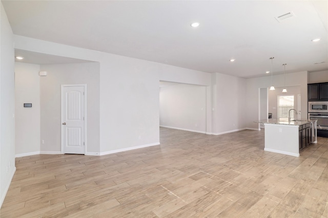 unfurnished living room with sink and light hardwood / wood-style floors