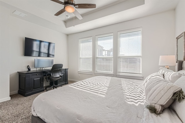 carpeted bedroom featuring a raised ceiling and ceiling fan