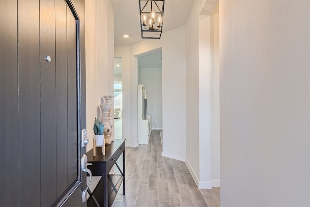 corridor featuring an inviting chandelier and light hardwood / wood-style flooring