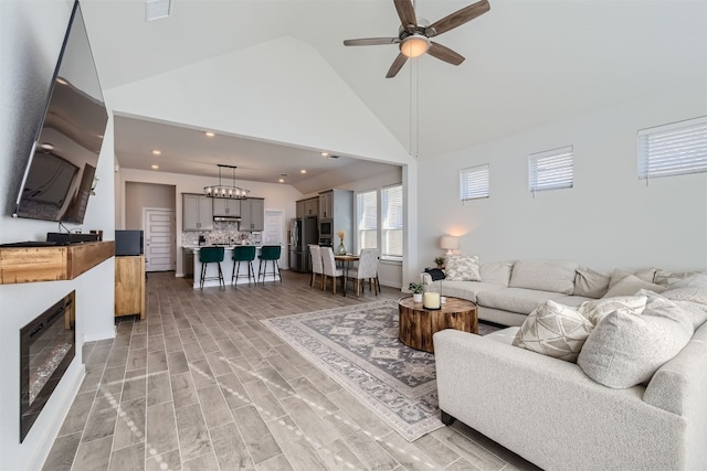 living room featuring ceiling fan, high vaulted ceiling, and light hardwood / wood-style flooring