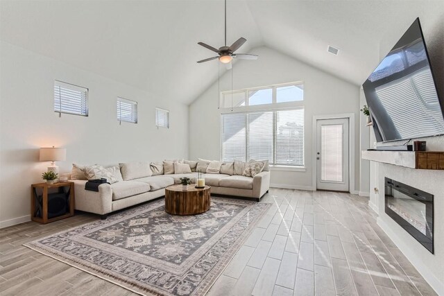 living room with light wood-type flooring, high vaulted ceiling, and ceiling fan