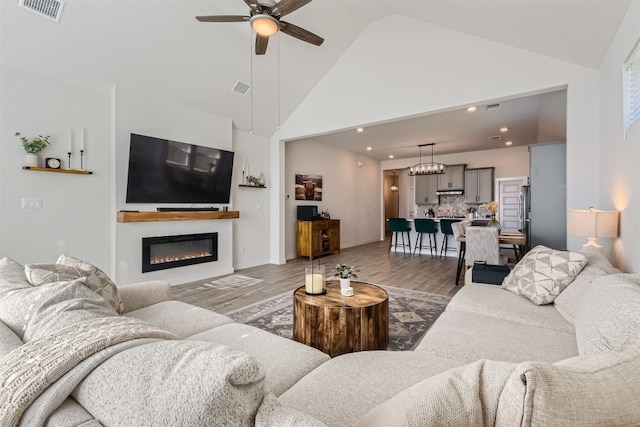 living room with ceiling fan, high vaulted ceiling, and hardwood / wood-style floors