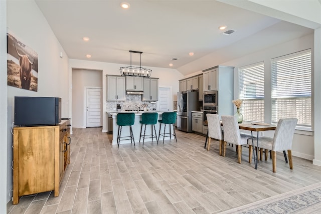 dining room featuring lofted ceiling, sink, and light hardwood / wood-style floors