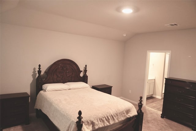 carpeted bedroom featuring ensuite bath and lofted ceiling