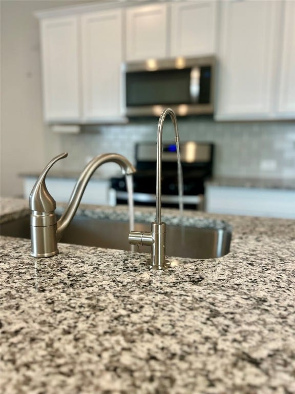 interior details with white cabinetry, stainless steel appliances, and light stone countertops