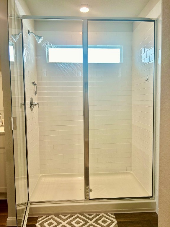 bathroom with a shower with shower door and wood-type flooring